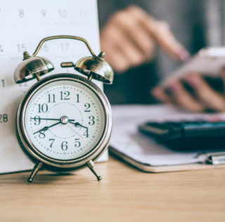 due date calendar and alarm clock with blur business woman hand calculating monthly expenses during tax season. L’imposition de la quote-part de frais et charges sur les dividendes constitue-t-elle une imposition du dividende ?