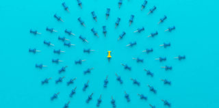 yellow push pin in the center of blue push pins with their spike turned to the yellow one as a concept of bullying or discrimination. conceptual photo of attack on person for opinion or views Port du voile : la CJUE précise et complète sa jurisprudence