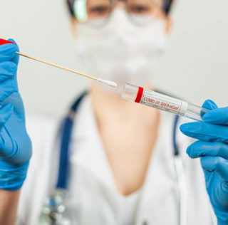 Test for coronavirus Covid-19. Female doctor or nurse doing lab analysis of a nasal swab in a hospital laboratory. Medical technologist holding a COVID-19 smear kit, wearing protective gloves from Le coût des tests de dépistage n’est pas un frais professionnel