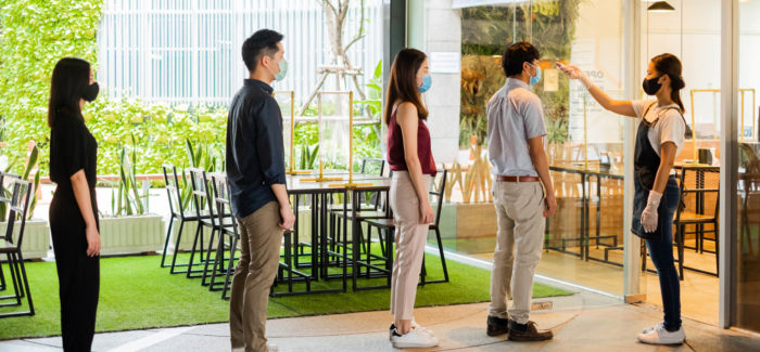 Asian waitress wear protective face mask scan customer temperature by thermometer before entering the restaurant to protect infection from coronavirus covid-19, social distancing concept Locaux de restauration : attention au respect des règles de distanciation physique