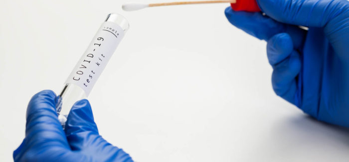 COVID-19 Coronavirus global pandemic, hands in gloves holding swab test tube, PCR at home patient sample collection kit,sterile specimen ready for analysis, detection testing presence of virus disease Pass sanitaire et obligation vaccinale : mise à jour des divers questions-réponses