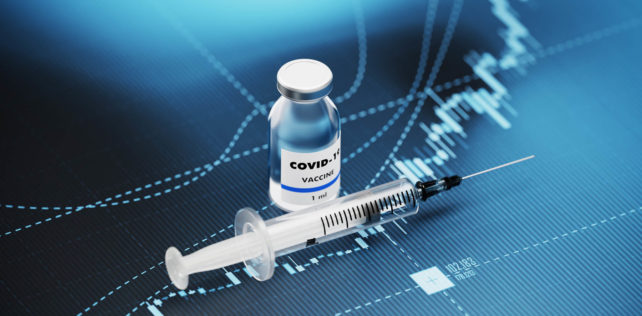 COVID-19 vaccine and syringe sitting over blue financial graph background. Selective focus. Horizontal composition with copy space. COVID-19 Vaccine and Stock market and finance concept. Covid-19 : renforcement des outils de gestion de la crise sanitaire