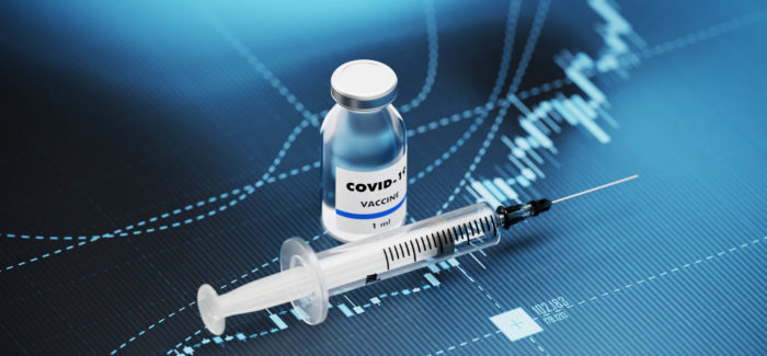 COVID-19 vaccine and syringe sitting over blue financial graph background. Selective focus. Horizontal composition with copy space. COVID-19 Vaccine and Stock market and finance concept. Covid-19 : renforcement des outils de gestion de la crise sanitaire