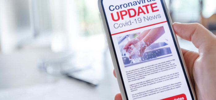 Close up of a mobile phone with Coronavirus covid-19 news update. The phone is being held and has an image of hand washing hygiene. There is paperwork on a table and home in the background. Copy space Fin du protocole national pour assurer la santé et la sécurité des salariés : que reste-t-il des mesures sanitaires en entreprise ?
