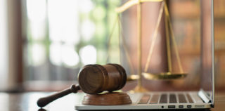 law legal technology concept. judge gavel on computer with scales of justice on desk of lawyer. La multiplication des demandes devant le Conseil de Prud’hommes (plus d’une dizaine) et leur montant élevé (582.000 euros au total) ne préjugent en rien de leur bien-fondé