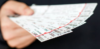 Tickets being held in a hand Les cadeaux dans le milieu professionnel : du rire aux larmes