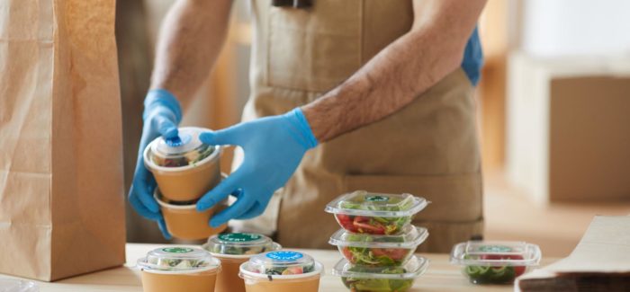 Closeup of unrecognizable worker wearing protective gloves packaging orders at wooden table in food delivery service, copy space CDD saisonnier : comment limiter les abandons de poste des travailleurs saisonniers ?