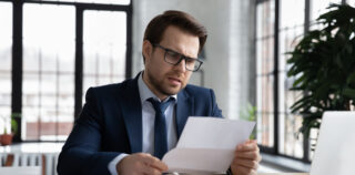Worried confused businessman reading letter at workplace, holding paper document. Business leader receiving bankruptcy or eviction notice, loan rejection from bank, getting bad news from mail Refus d’une modification du contrat de travail pour motif économique : attention à la rédaction de la lettre de licenciement !