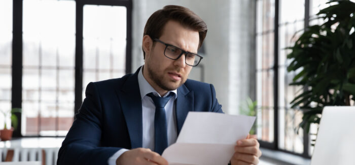 Worried confused businessman reading letter at workplace, holding paper document. Business leader receiving bankruptcy or eviction notice, loan rejection from bank, getting bad news from mail Refus d’une modification du contrat de travail pour motif économique : attention à la rédaction de la lettre de licenciement !