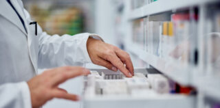 Male pharmacist choosing a medicine from the drawer, side view. Exercice d’une activité réglementée : n’omettez pas de vérifier que vos salariés sont en possession des diplômes nécessaires !