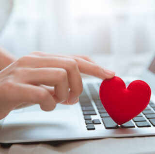 Hand touching red heart on laptop keyboard for flirt love chat or lover online text messenger for find date couple during stay home Coronavirus pandemic situation Ne pas informer son employeur d’une relation intime avec un autre salarié peut justifier un licenciement disciplinaire