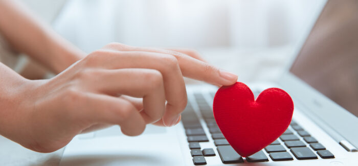 Hand touching red heart on laptop keyboard for flirt love chat or lover online text messenger for find date couple during stay home Coronavirus pandemic situation Ne pas informer son employeur d’une relation intime avec un autre salarié peut justifier un licenciement disciplinaire