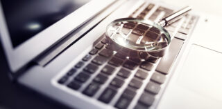Magnifying glass on laptop keyboard searc for online documents background Conditions de production d’une preuve illicite ou déloyale : une jurisprudence réaffirmée
