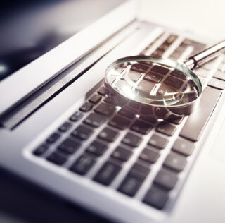 Magnifying glass on laptop keyboard searc for online documents background Conditions de production d’une preuve illicite ou déloyale : une jurisprudence réaffirmée