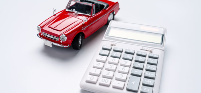 Calculator and sports car isolated on white background TVA : véhicules de tourisme mis à disposition des salariés