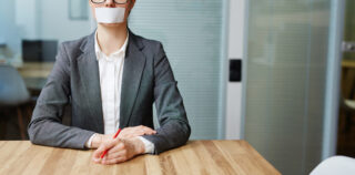 Voiceless busineswoman with her mouth stuck sitting by workplace Entretien préalable : faut-il informer le salarié de son droit de se taire ?