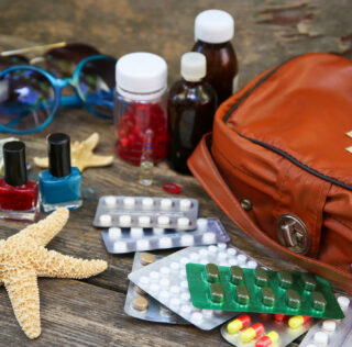 Summer women's beach accessories for your sea holiday and first aid kit on old wooden background. Concept of medication required in journey. Maladie et congés payés : nouvelles perspectives