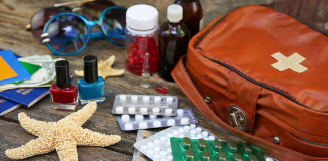 Summer women's beach accessories for your sea holiday and first aid kit on old wooden background. Concept of medication required in journey. Maladie et congés payés : nouvelles perspectives