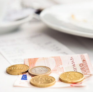 A Euro note and coins to pay a cafe breakfast bill. La cour d’appel de Versailles estime que les titres-restaurant relèvent des activités sociales et culturelles
