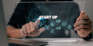 Start-up concept with icons for business and network connection on a modern virtual interface from a tablet computer. Man is putting his finger on the tablet. DRH de Start-up : comment réussir ses premières élections professionnelles ?
