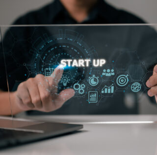 Start-up concept with icons for business and network connection on a modern virtual interface from a tablet computer. Man is putting his finger on the tablet. DRH de Start-up : comment réussir ses premières élections professionnelles ?