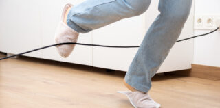 Close up of a woman legs stumbling with an electrical cord at home La difficile contestation du caractère professionnel de l’accident déclaré en situation de télétravail