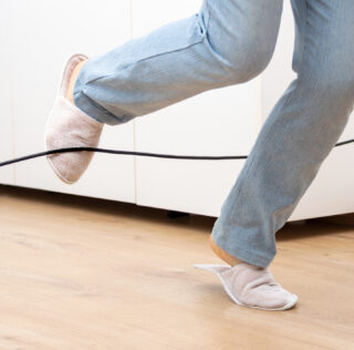 Close up of a woman legs stumbling with an electrical cord at home La difficile contestation du caractère professionnel de l’accident déclaré en situation de télétravail